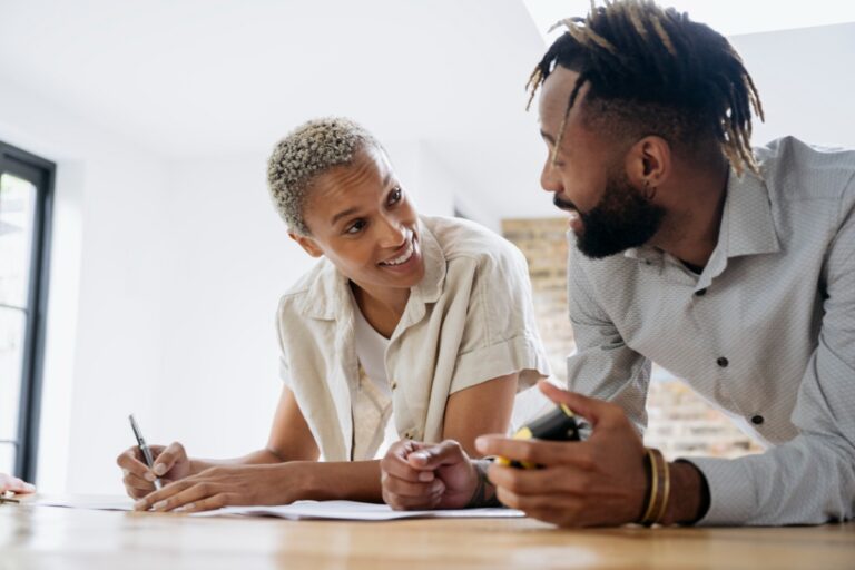 Man and woman discussing how much life insurance they need with paperwork and calculator
