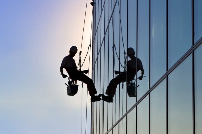 Window cleaner suspended from a high-rise building, performing a high-risk occupation