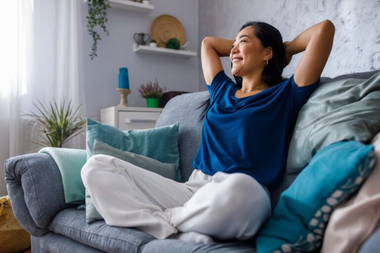 A happy single woman sitting on a couch relieved that she has life insurance