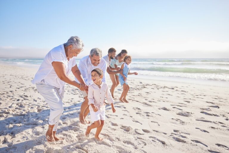 grandparents playing with grandson on beach vacation